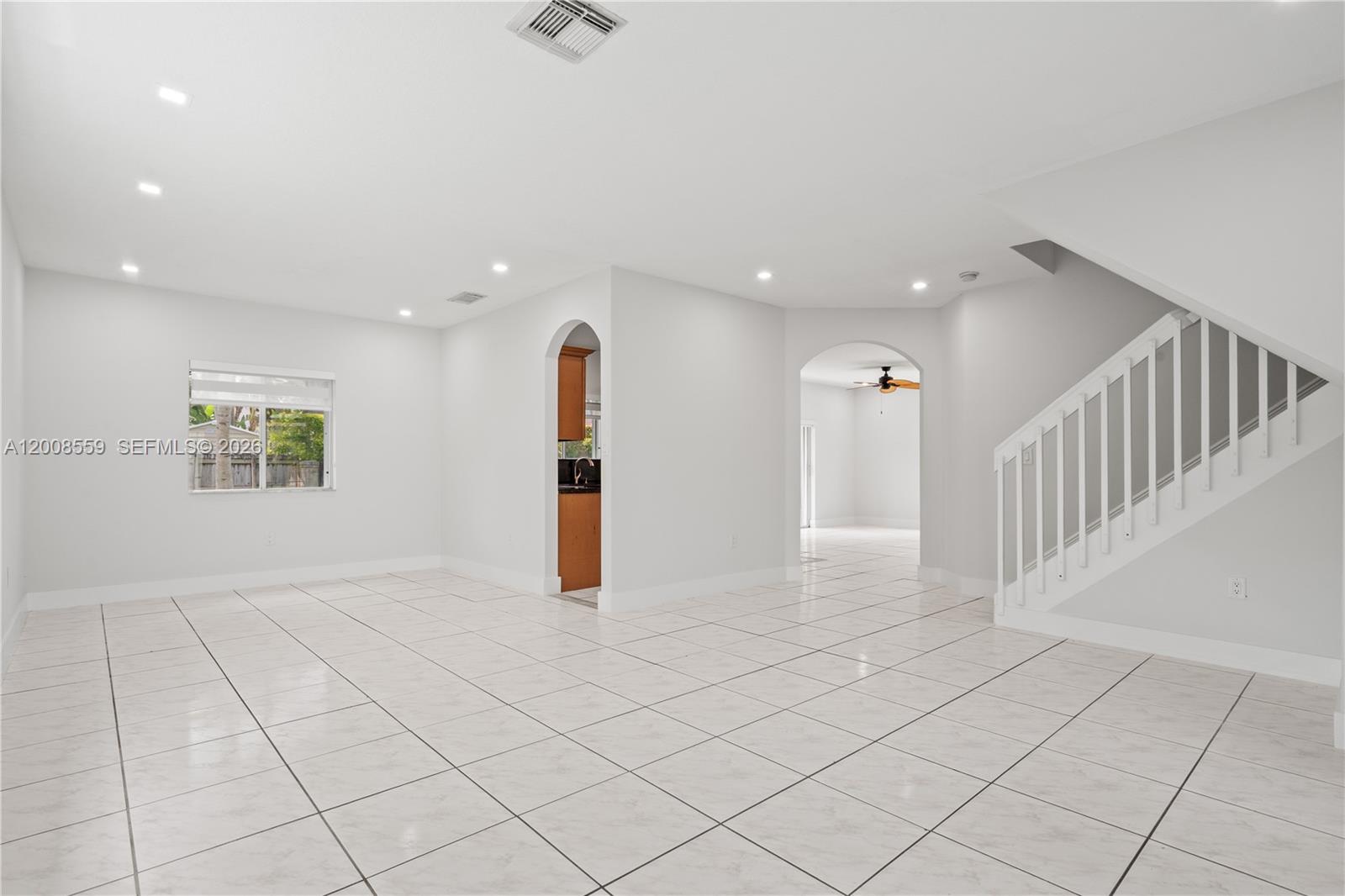 A bright, tiled living area features white walls, a staircase, and arched doorways — 9576 SW 162nd Path, Miami FL 33196, MIAMI, FL