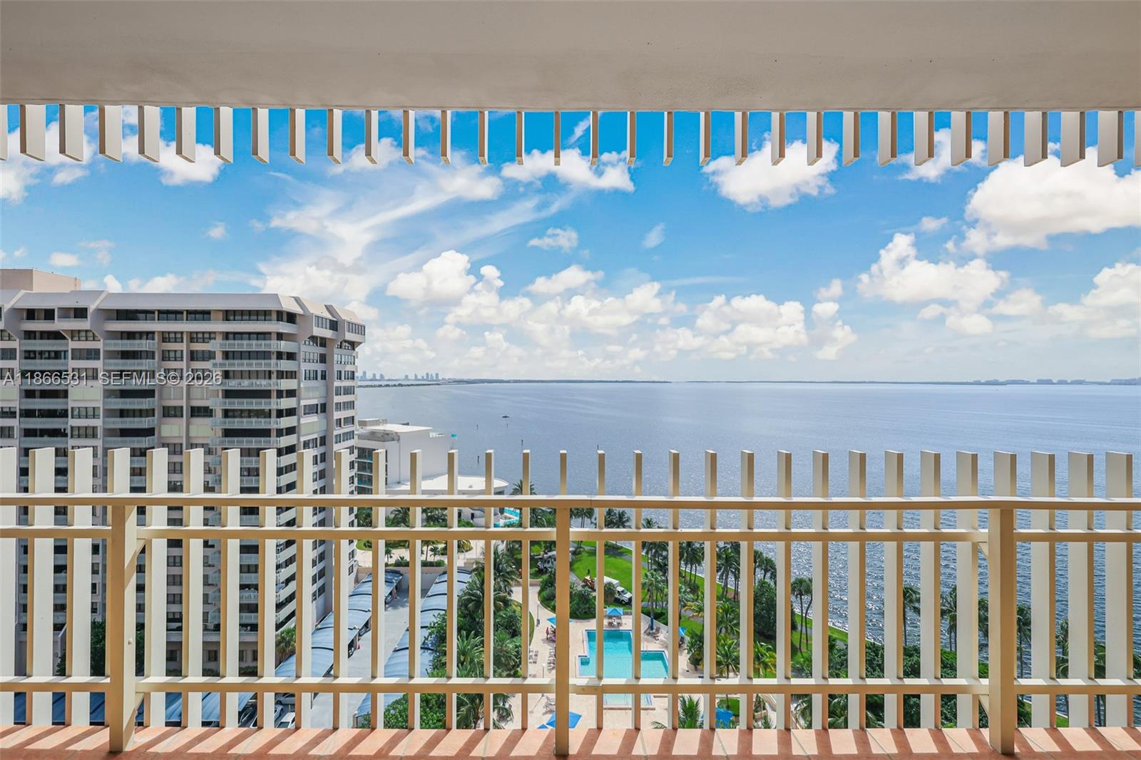 A balcony with a white railing overlooks a swimming pool, palm trees, and the ocean — 2 Grove Isle Dr # B1603, Miami FL 33133, MIAMI, FL