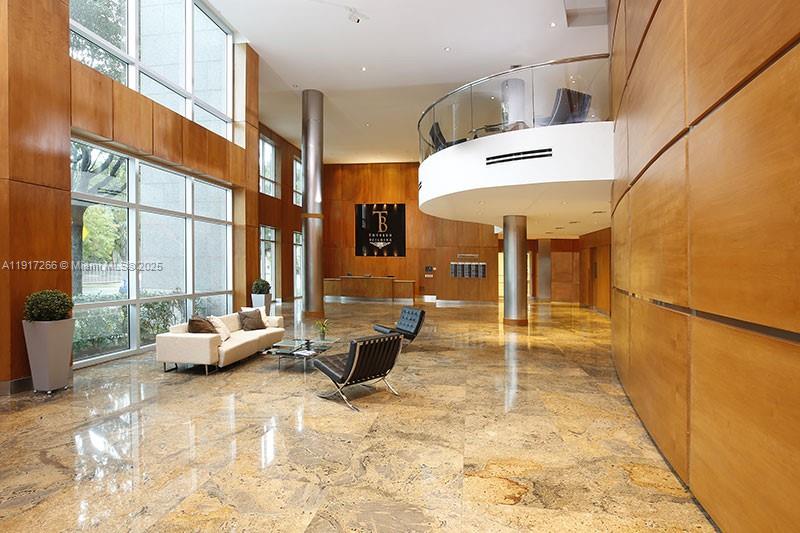A spacious lobby features wood-paneled walls, a marble floor, and a curved mezzanine balcony — 1000 5th St # 102, Miami Beach FL 33139, MIAMI BEACH, FL