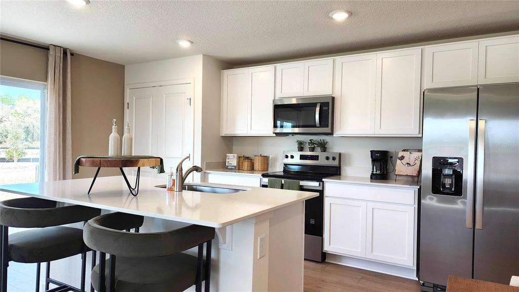 A modern kitchen features white cabinets, stainless steel appliances, and a large central island — 550 REMICK STREET, OSTEEN, FL
