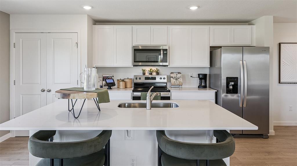 A modern kitchen features white cabinets, stainless steel appliances, and a large central island — 550 REMICK STREET, OSTEEN, FL
