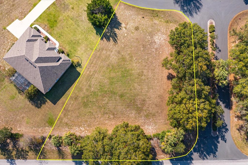 An aerial view shows a vacant, irregularly shaped residential lot bordered by trees and roads — 1001 MYRTLE BREEZES COURT, FRUITLAND PARK, FL