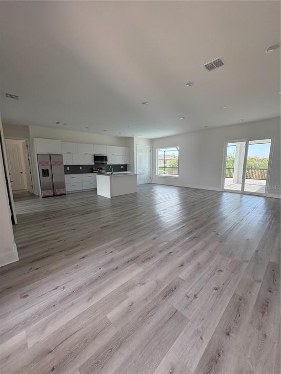 An open-concept kitchen and living area features white cabinetry, a center island, and wood flooring — 15384 HENNIPEN CIRCLE, PORT CHARLOTTE, FL