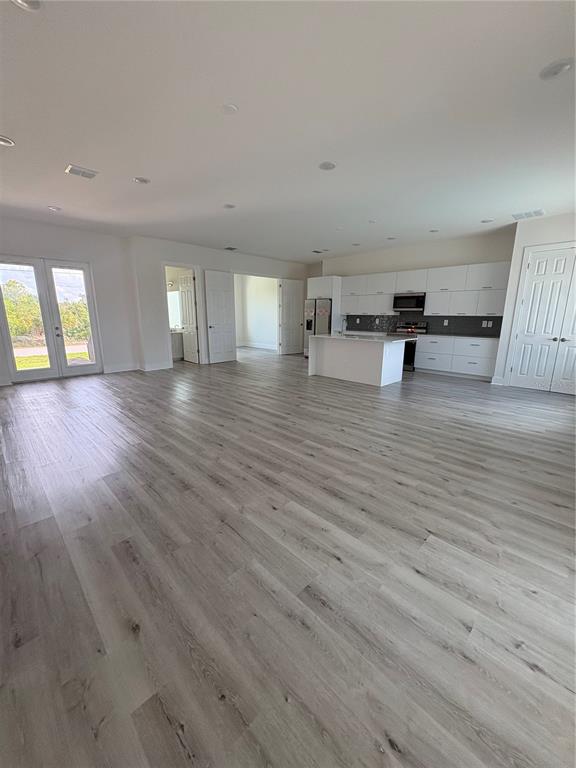 An open-concept kitchen and living area features white cabinetry, a center island, and wood-look flooring — 15384 HENNIPEN CIRCLE, PORT CHARLOTTE, FL