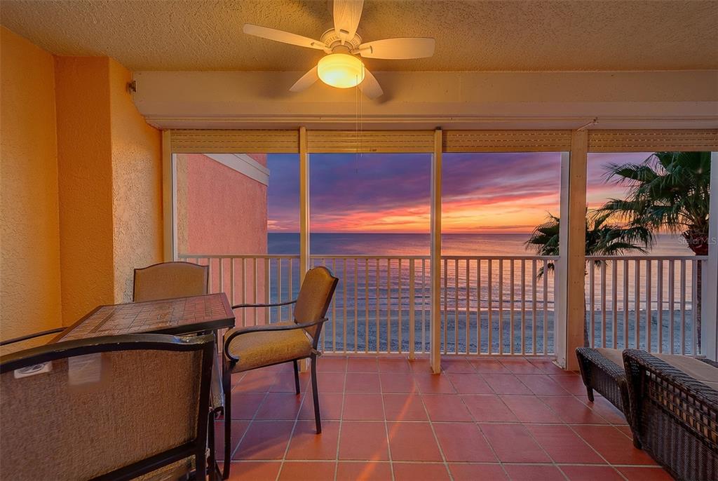 A screened-in balcony with red tile flooring overlooks the ocean and a palm tree — 16450 GULF BOULEVARD UNIT 565, NORTH REDINGTON BEACH, FL