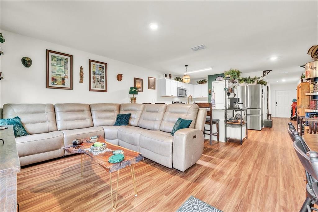 A living room with a large sectional sofa, a live-edge coffee table, and an open kitchen — 28087 CHINQUAPIN DRIVE, PUNTA GORDA, FL