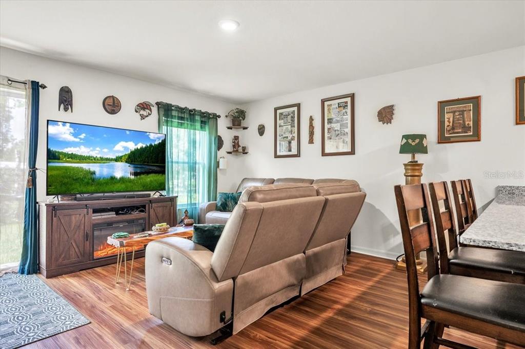 A living room features a television on a media console, a reclining sofa, and wood-look flooring — 28087 CHINQUAPIN DRIVE, PUNTA GORDA, FL