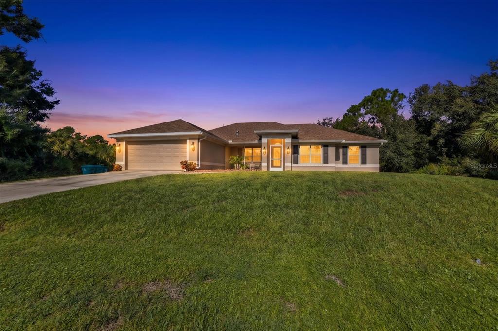 A single-story house with a tan exterior, a two-car garage, and a grassy front yard — 101 FITZSIMONS STREET, PORT CHARLOTTE, FL