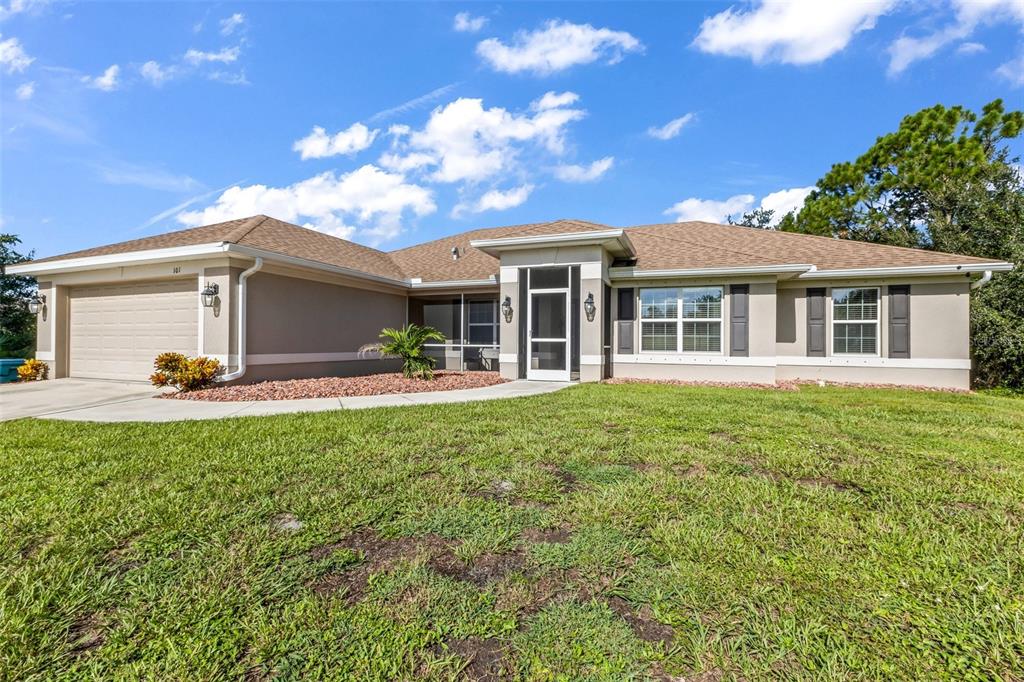 A single-story suburban house with a tan stucco exterior, brown roof, and attached two-car garage — 101 FITZSIMONS STREET, PORT CHARLOTTE, FL