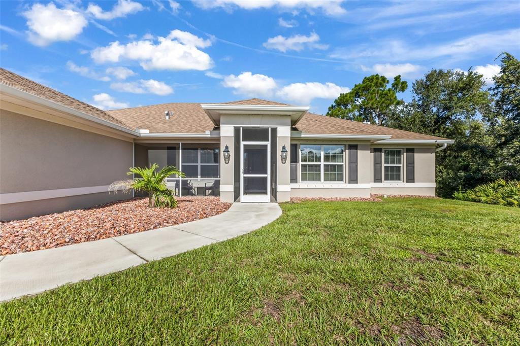 A single-story house with a screened entryway, tan stucco walls, and a brown shingled roof — 101 FITZSIMONS STREET, PORT CHARLOTTE, FL