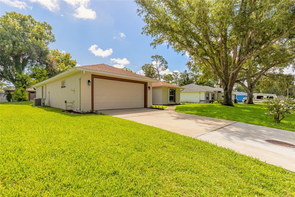 A single-story house with a beige exterior, a two-car garage, and a large front lawn — 2919 OAK LEA DRIVE, SOUTH DAYTONA, FL