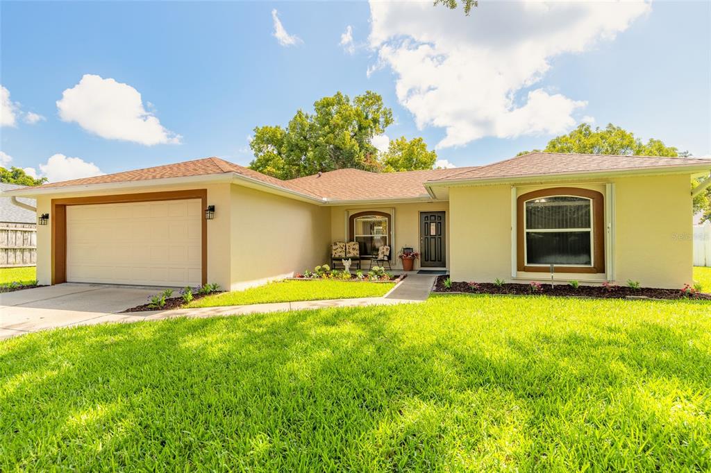 A single-story house with a two-car garage, light yellow stucco exterior, and a front lawn — 2919 OAK LEA DRIVE, SOUTH DAYTONA, FL