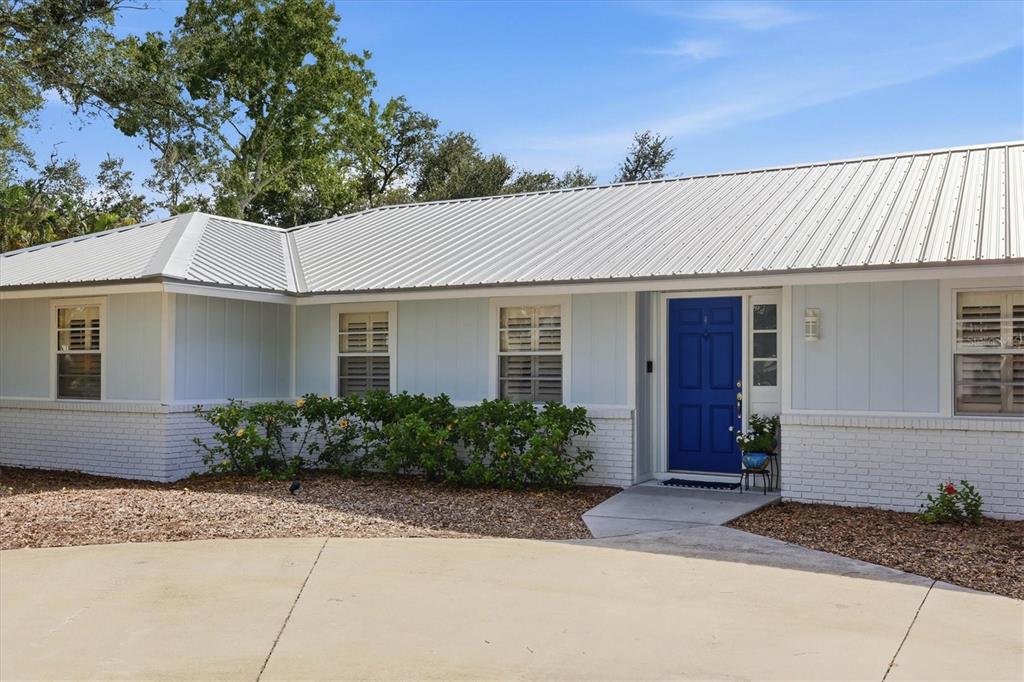 A single-story house with light blue siding, a white brick base, and a blue front door — 5505 BENEVA WOODS CIRCLE, SARASOTA, FL