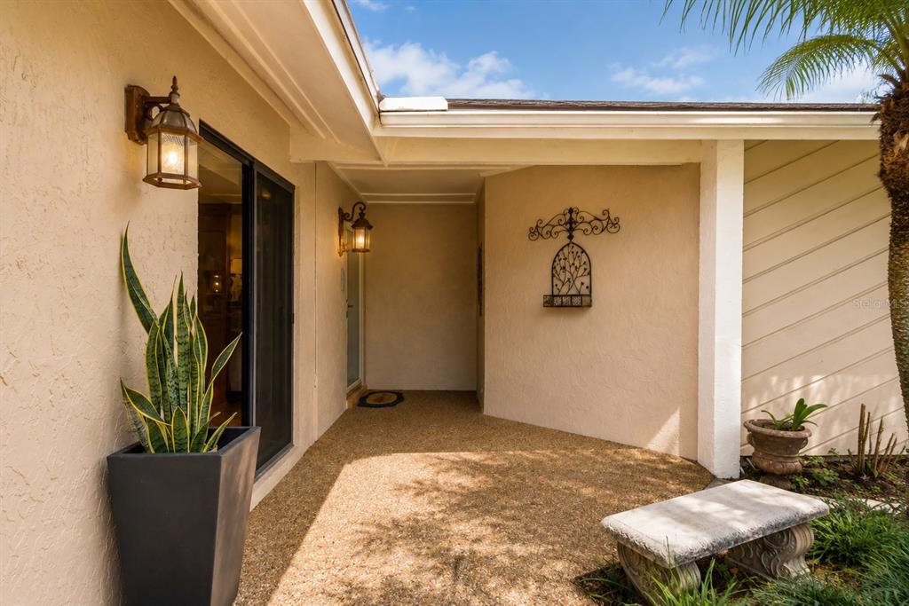 A covered entryway features a gravel floor, a stone bench, and two wall-mounted lanterns — 787 EVERT COURT, WINTER SPRINGS, FL