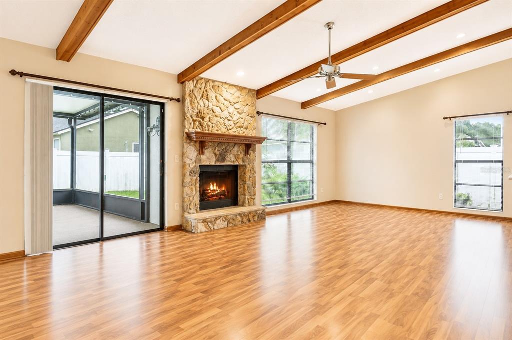 A living room with wood-look flooring, a stone fireplace, and exposed wooden ceiling beams — 787 EVERT COURT, WINTER SPRINGS, FL