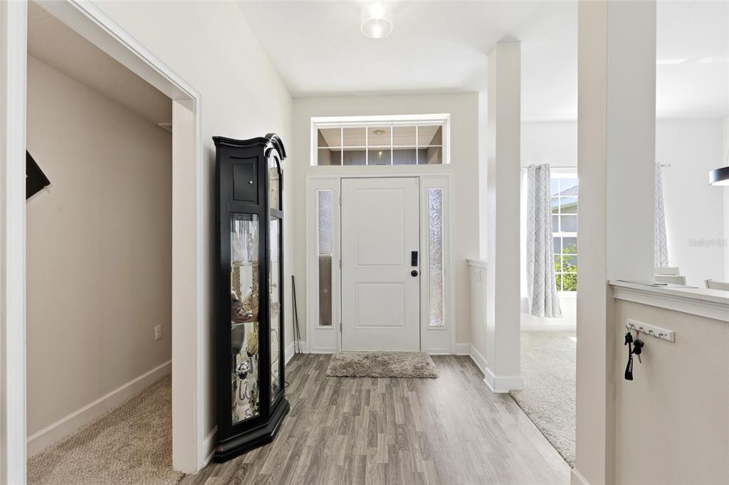 An entryway features wood-look flooring, a white front door with sidelights, and a black display cabinet — 5513 MYRTLE DRIVE, FORT PIERCE, FL