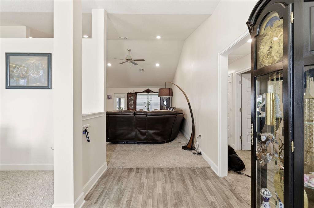 A hallway with wood-look flooring leads into a carpeted living room with a vaulted ceiling — 5513 MYRTLE DRIVE, FORT PIERCE, FL