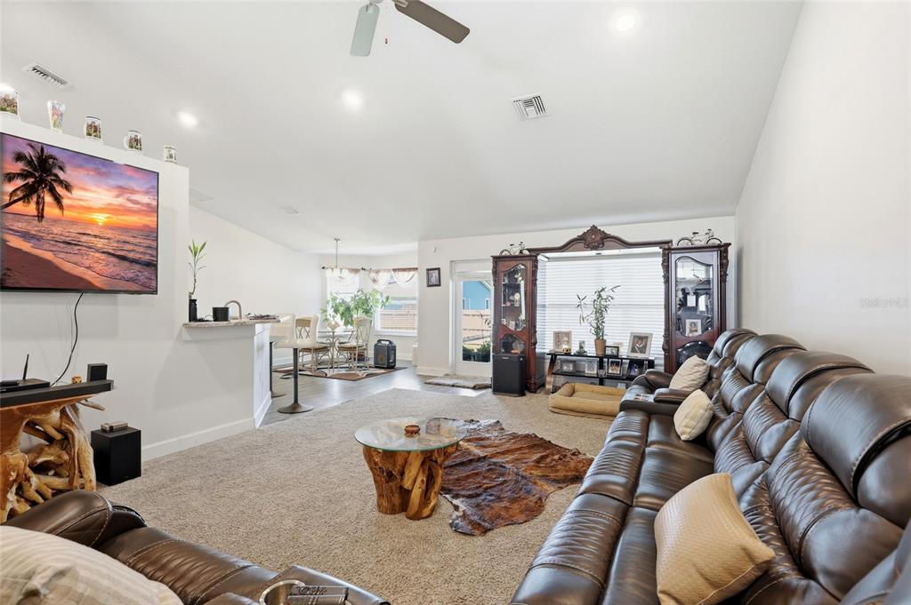 A living room features a large leather sofa, a glass-topped coffee table, and a television — 5513 MYRTLE DRIVE, FORT PIERCE, FL