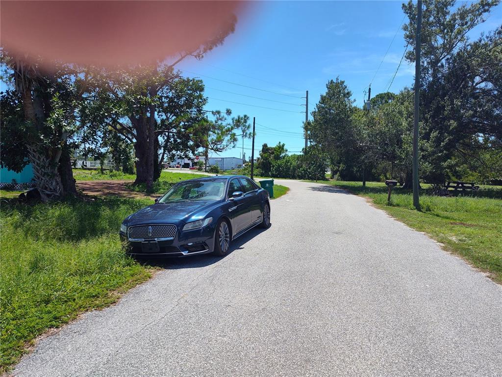 A dark blue sedan is parked on the shoulder of a paved road near trees — 8329 ROOSEVELT STREET, ENGLEWOOD, FL