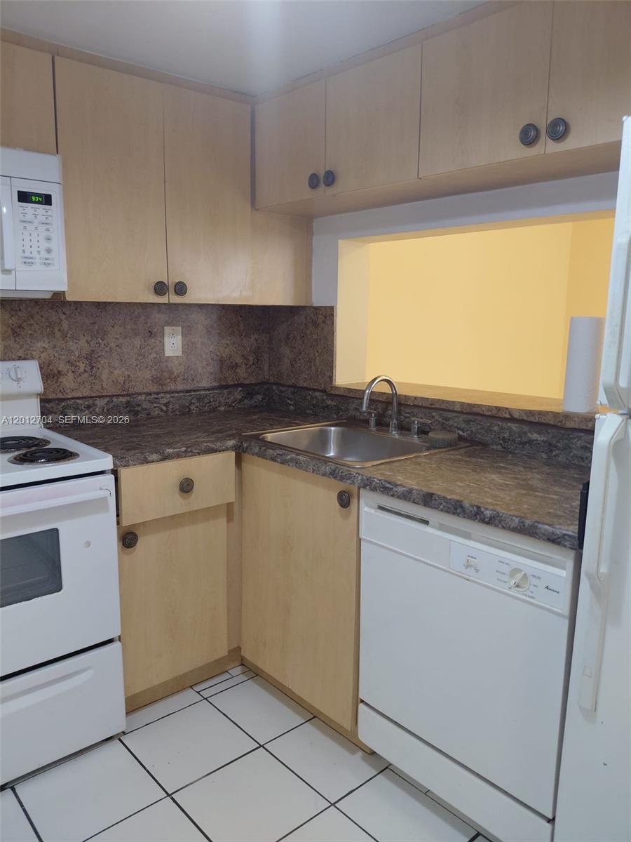 A kitchen features light wood cabinets, dark laminate countertops, white appliances, and white tile flooring — 11790 SW 18th St # 3, Miami FL 33175, MIAMI, FL