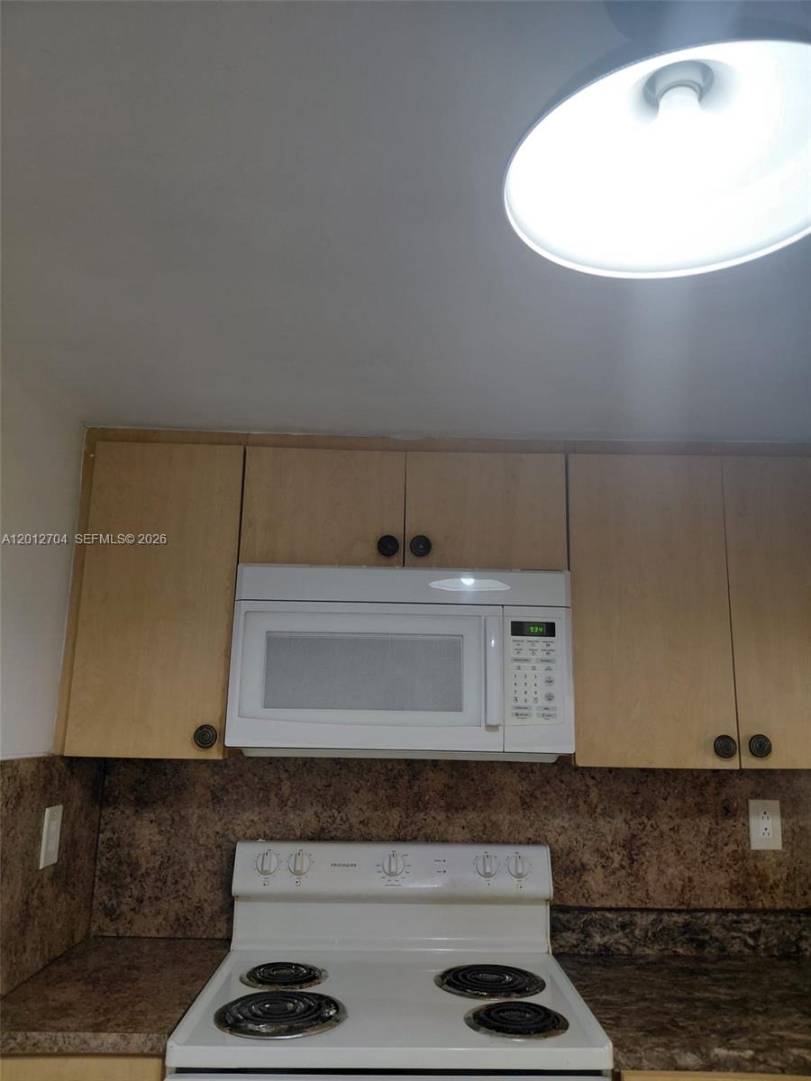 A kitchen features light wood cabinets, a white microwave, and a white electric stove — 11790 SW 18th St # 3, Miami FL 33175, MIAMI, FL