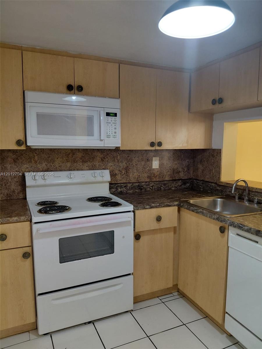 A kitchen features light wood cabinets, white appliances, and dark laminate countertops — 11790 SW 18th St # 3, Miami FL 33175, MIAMI, FL