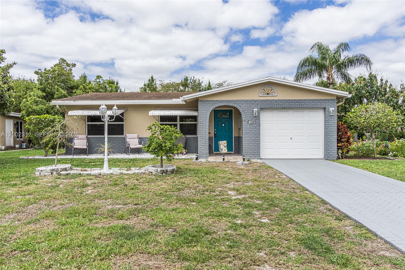 A single-story house with a gray brick facade, teal front door, and a paved driveway — 4871 NW 13th Ave, Deerfield Beach FL 33064, DEERFIELD BEACH, FL