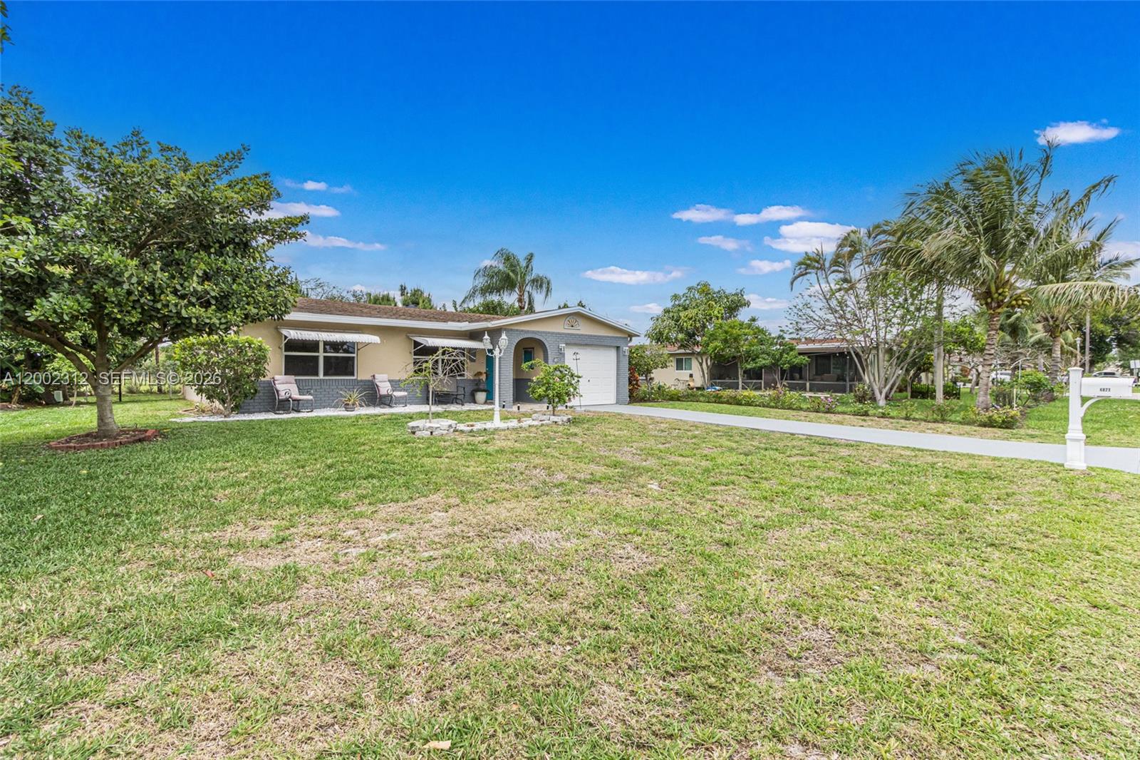 A single-story house with a gray brick facade, white garage door, and a large lawn — 4871 NW 13th Ave, Deerfield Beach FL 33064, DEERFIELD BEACH, FL