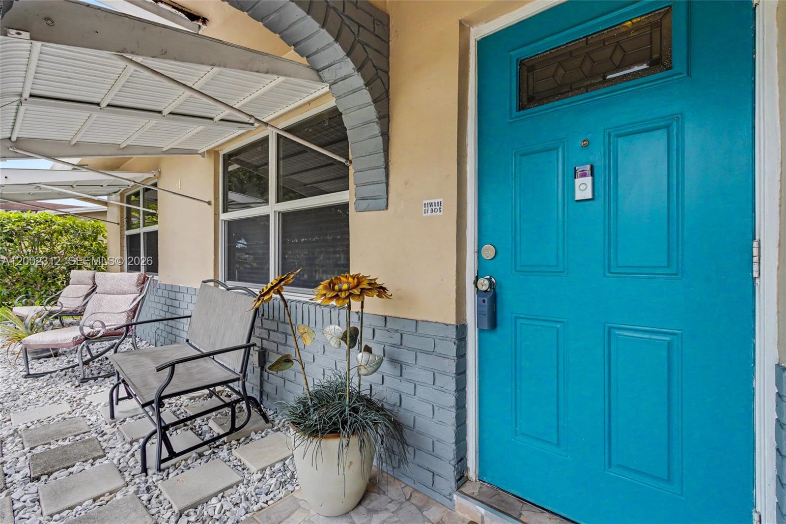 A bright blue front door sits beside a gray brick wall and a patio area — 4871 NW 13th Ave, Deerfield Beach FL 33064, DEERFIELD BEACH, FL