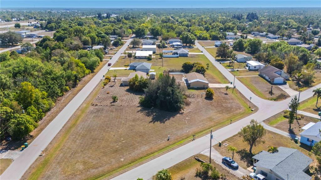An aerial view shows a large, grassy residential lot situated at a street intersection — 11131 2ND AVENUE, PUNTA GORDA, FL