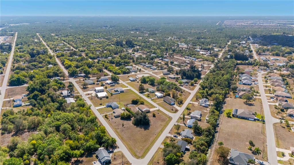 An aerial view shows a suburban neighborhood with scattered houses, paved roads, and wooded areas — 11131 2ND AVENUE, PUNTA GORDA, FL