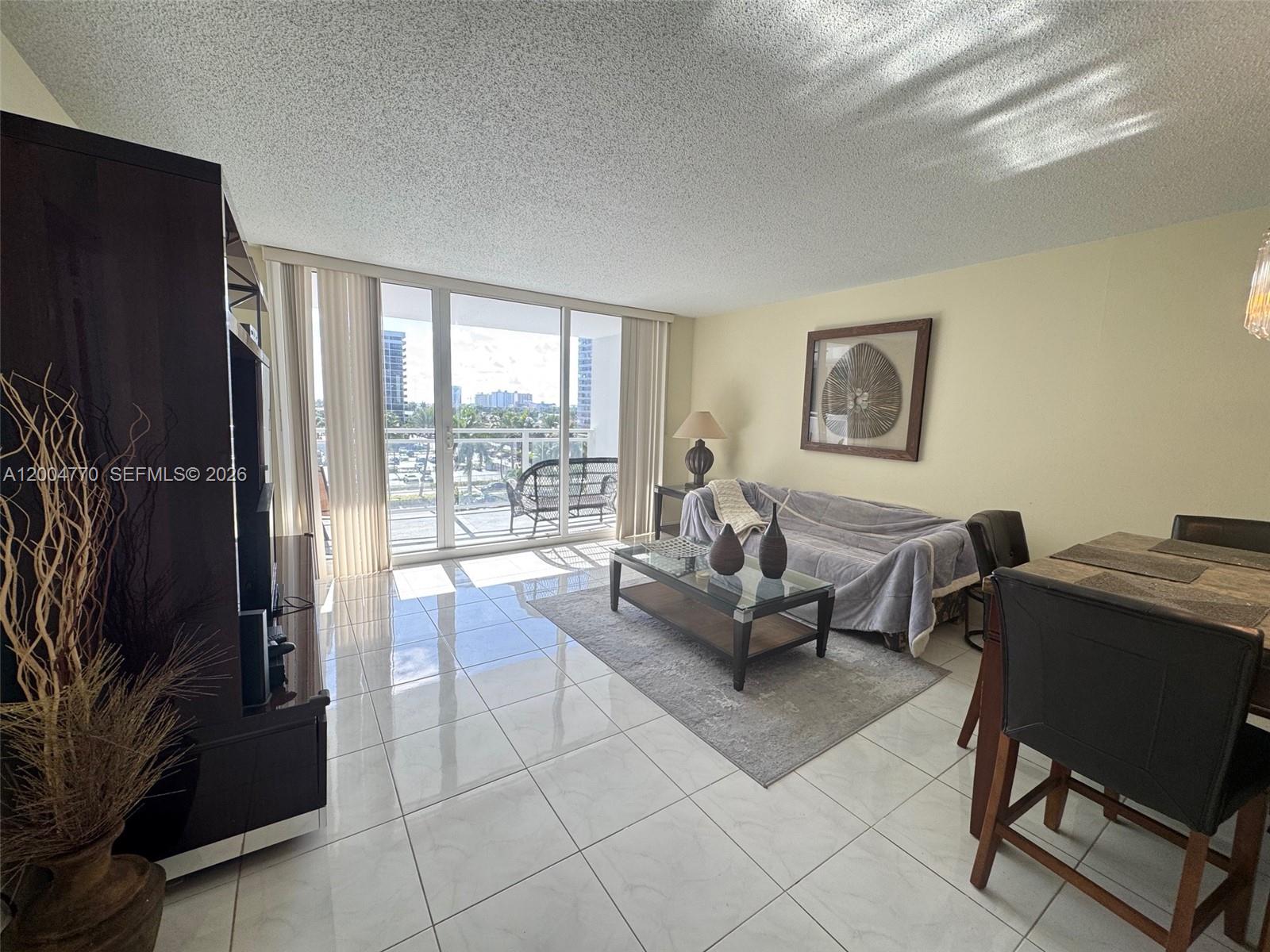 A living room with tile floors, a glass coffee table, and a balcony with views — 2030 S Ocean Dr # 403, Hallandale Beach FL 33009, HALLANDALE BEACH, FL
