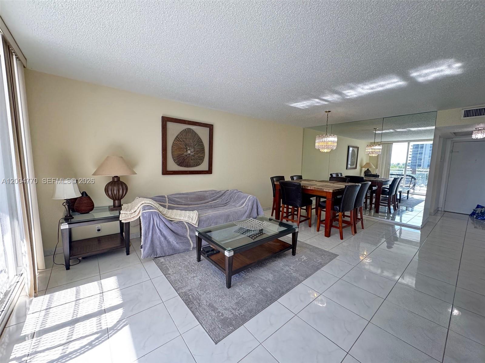 A living and dining area features white tile floors, a mirrored wall, and a glass-topped table — 2030 S Ocean Dr # 403, Hallandale Beach FL 33009, HALLANDALE BEACH, FL