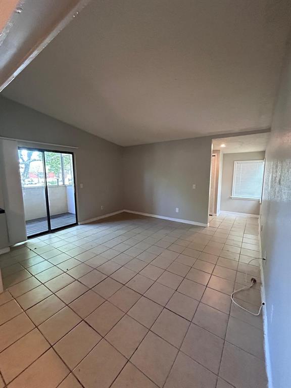 An empty living room features light-colored tile flooring, neutral walls, and a sliding glass door — 2948 ANTIQUE OAKS CIRCLE UNIT 94, WINTER PARK, FL