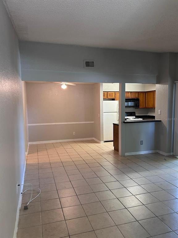 An open-concept dining area with tile flooring leads into a kitchen with wood cabinets — 2948 ANTIQUE OAKS CIRCLE UNIT 94, WINTER PARK, FL