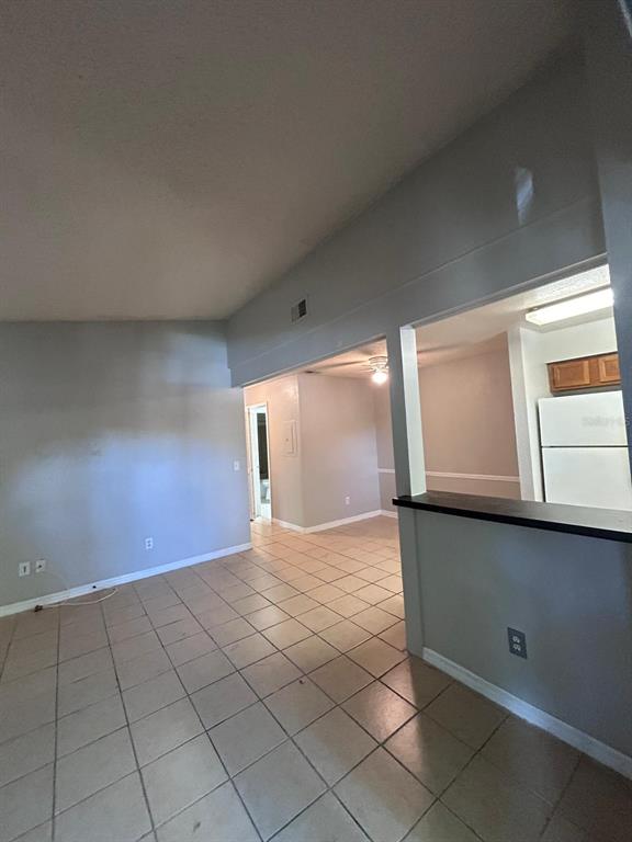 A living area with tile flooring opens into a kitchen with a breakfast bar — 2948 ANTIQUE OAKS CIRCLE UNIT 94, WINTER PARK, FL