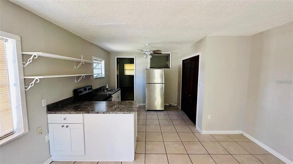 A kitchen features white cabinets, a granite countertop, stainless steel appliances, and tile flooring — 1310 N COMBEE ROAD UNIT 7, LAKELAND, FL