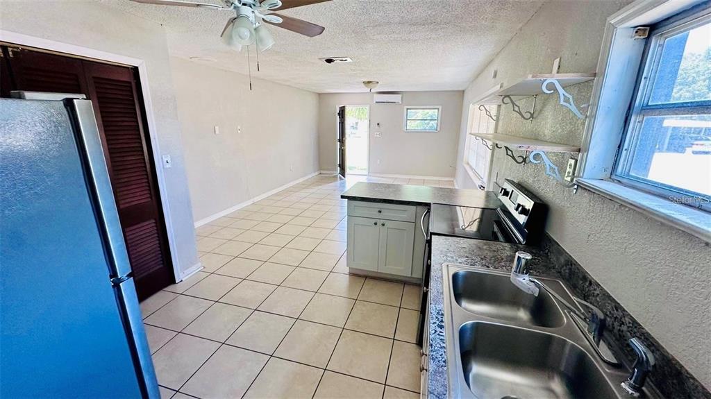 A kitchen with tile floors, stainless steel sink, and open living area with ceiling fan — 1310 N COMBEE ROAD UNIT 7, LAKELAND, FL