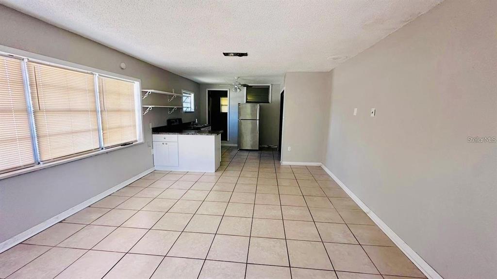 An open-concept kitchen and living area features light tile flooring and white cabinetry — 1310 N COMBEE ROAD UNIT 7, LAKELAND, FL