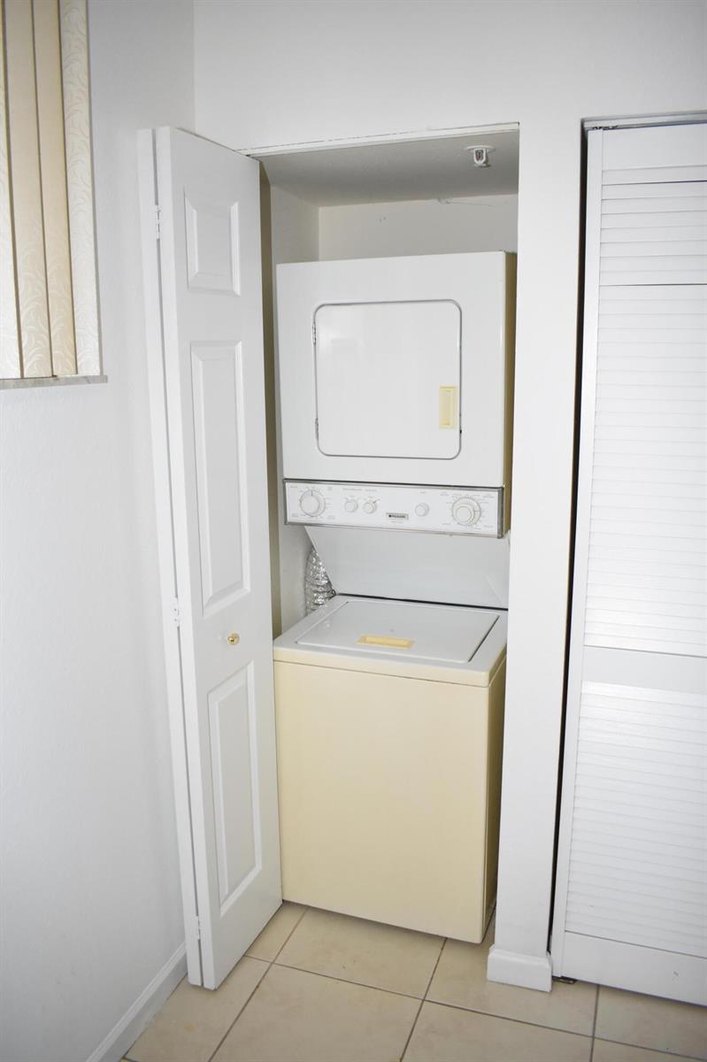 A stacked washer and dryer unit sits inside a small closet with white doors — 1954 Marsh Harbor Drive # 101, Riviera Beach FL 33404, RIVIERA BEACH, FL