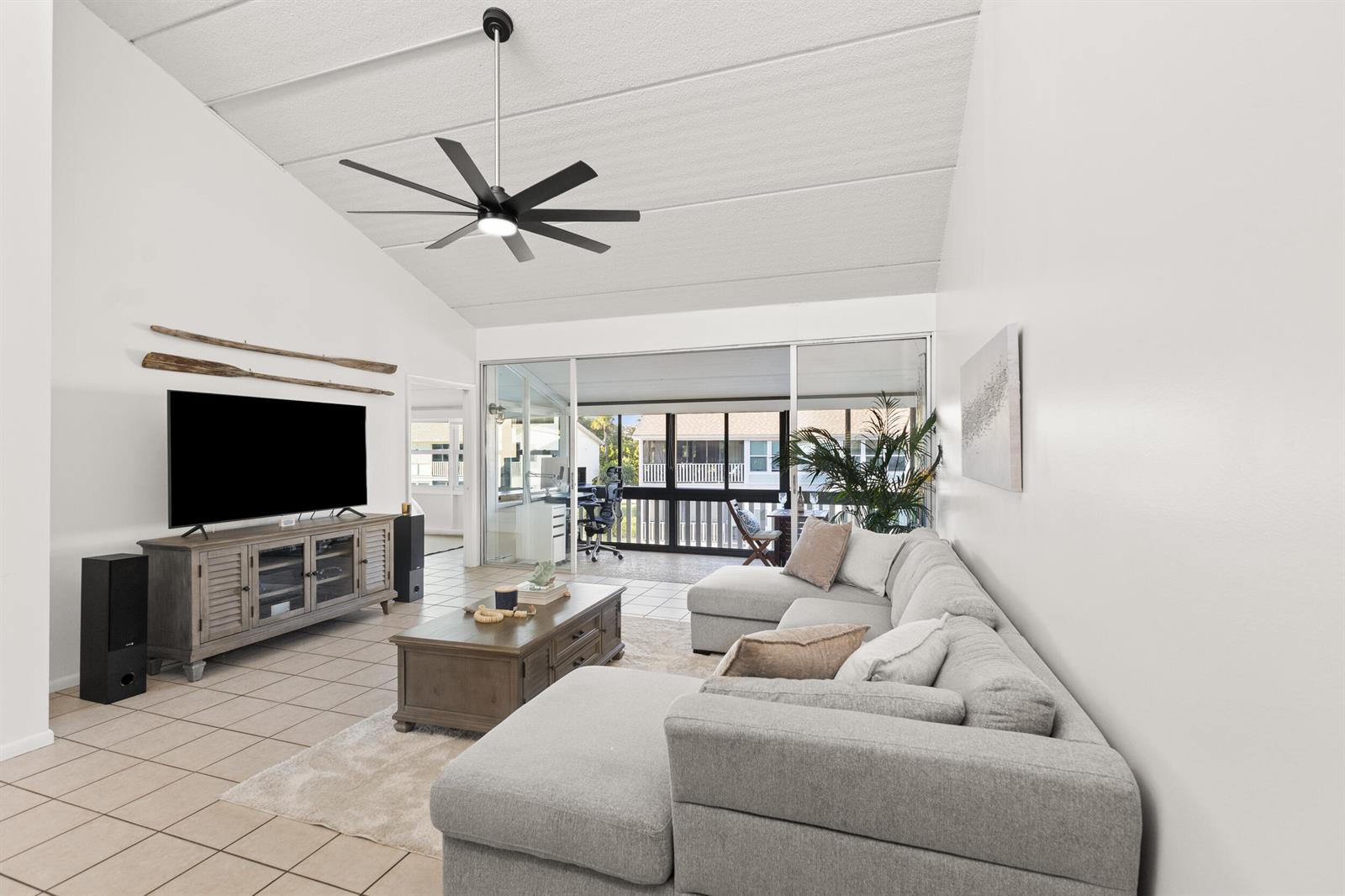 A living room features a vaulted ceiling, a large sectional sofa, and a sliding door — 1456 NE Ocean Boulevard # 202, Stuart FL 34996, STUART, FL