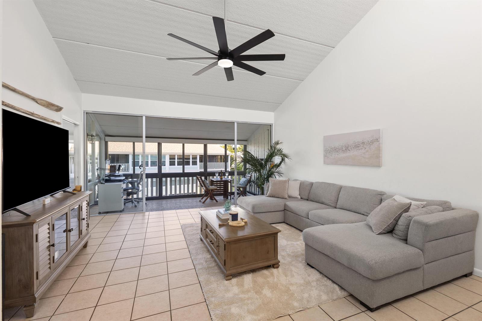 A living room features a gray sectional sofa, wood coffee table, and a large ceiling fan — 1456 NE Ocean Boulevard # 202, Stuart FL 34996, STUART, FL