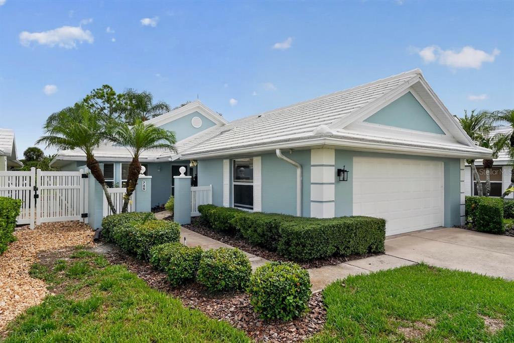 A light blue house with a white tile roof, garage, and manicured landscaping — 746 HARRINGTON LAKE DRIVE N UNIT 117, VENICE, FL