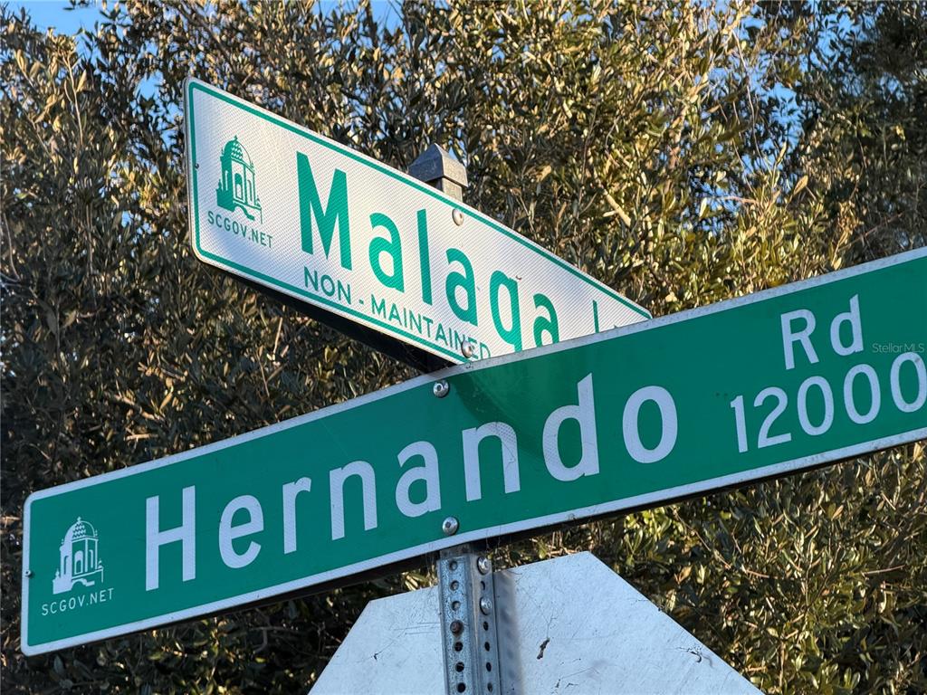 Two street signs for Malaga and Hernando Road are mounted on a metal pole — Lots 35 & 36 HERNANDO ROAD, NORTH PORT, FL