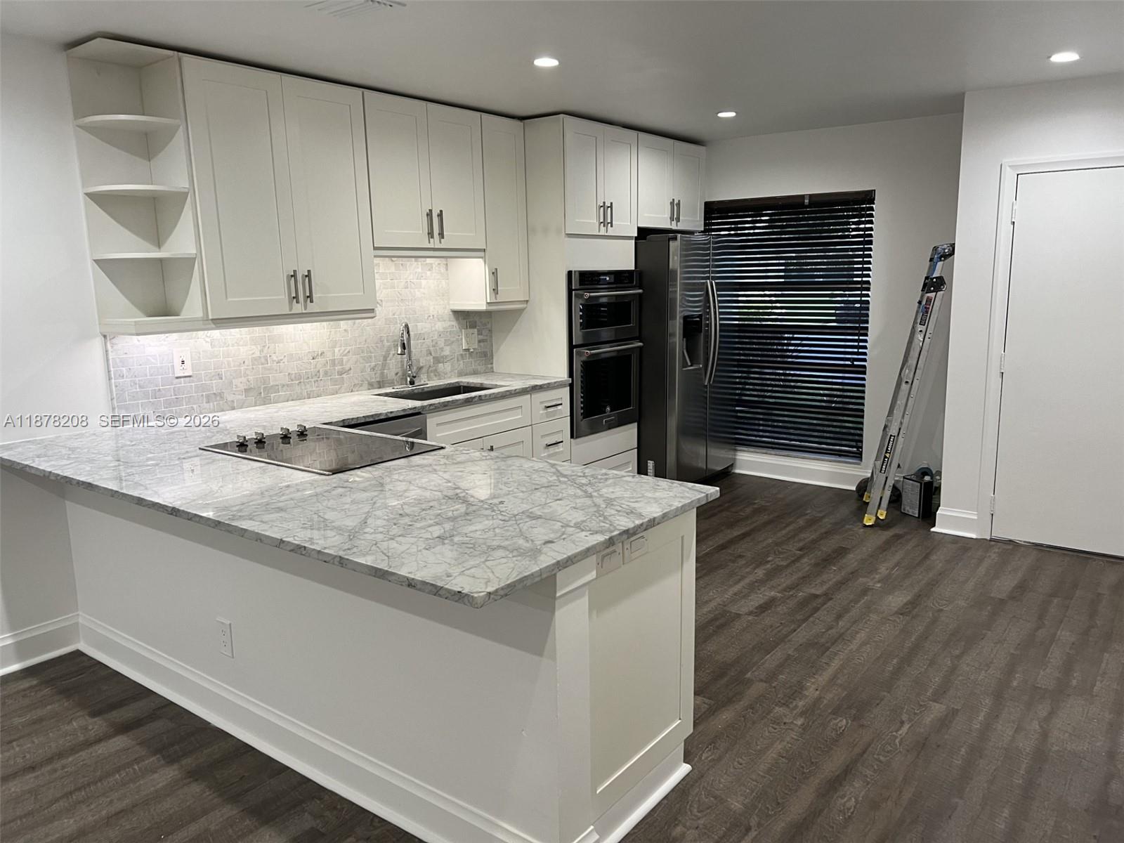 A kitchen features white cabinetry, marble countertops, a stainless steel oven, and dark wood flooring — 20927 Sedgewick Dr # 20927, Boca Raton FL 33433, BOCA RATON, FL