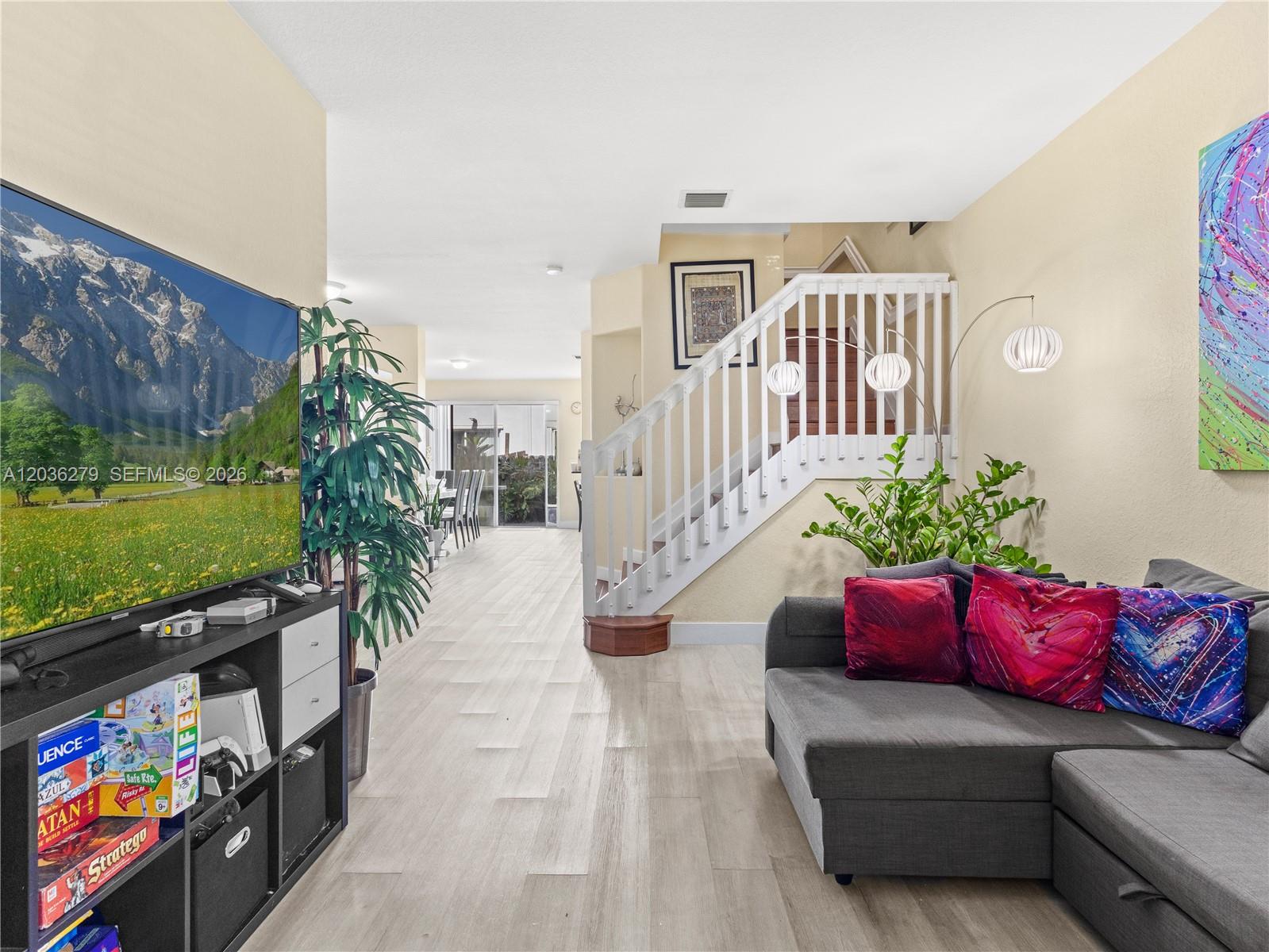 A living room features a grey sectional sofa, a television, and a white staircase — 8128 NW 108th Ct # 8128, Doral FL 33178, DORAL, FL