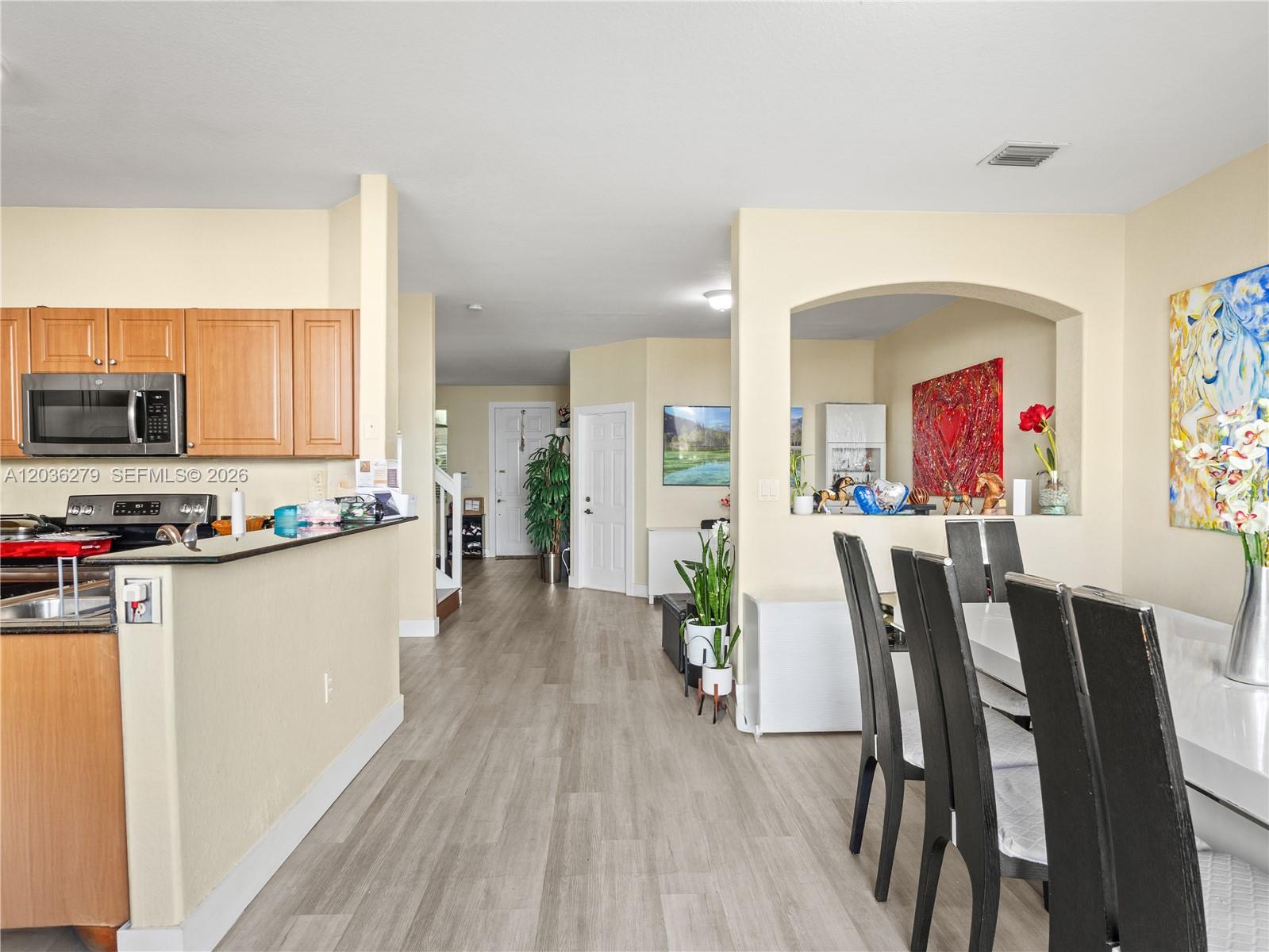 A kitchen with light wood cabinets opens into a dining area with black chairs — 8128 NW 108th Ct # 8128, Doral FL 33178, DORAL, FL