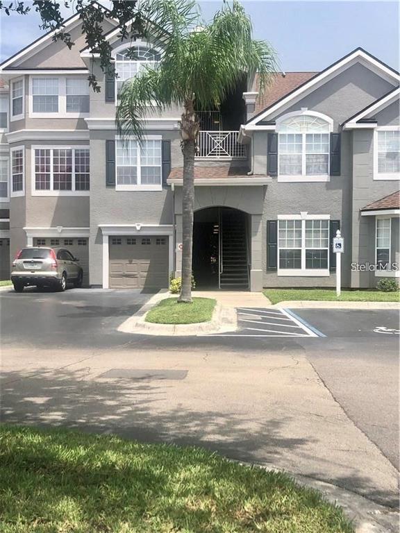 A three-story gray apartment building features a palm tree, a garage, and a parking lot — 3325 S KIRKMAN ROAD UNIT 423, ORLANDO, FL