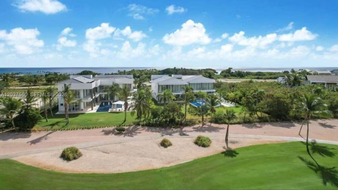 An aerial view shows two modern white houses with swimming pools near a coastal landscape — 0 Caleton estate 1, FL