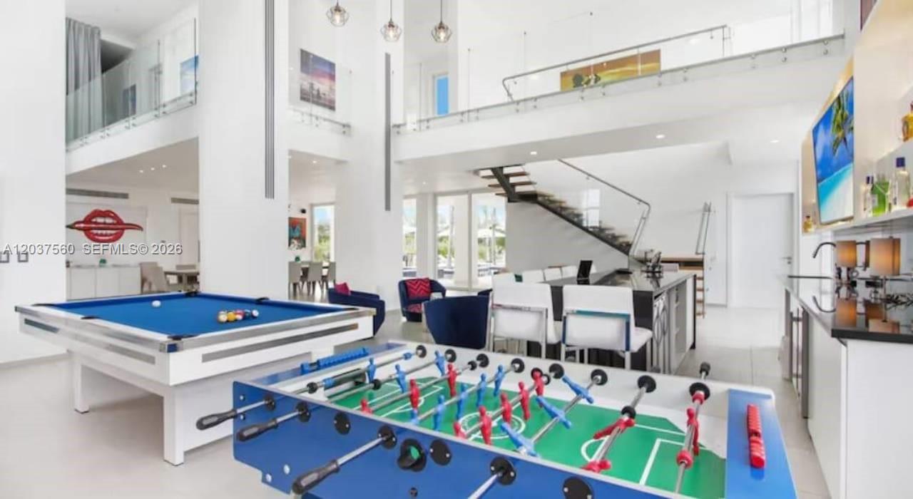 A spacious, modern living area features a pool table, foosball table, and a floating staircase — 0 Caleton estate 1, FL